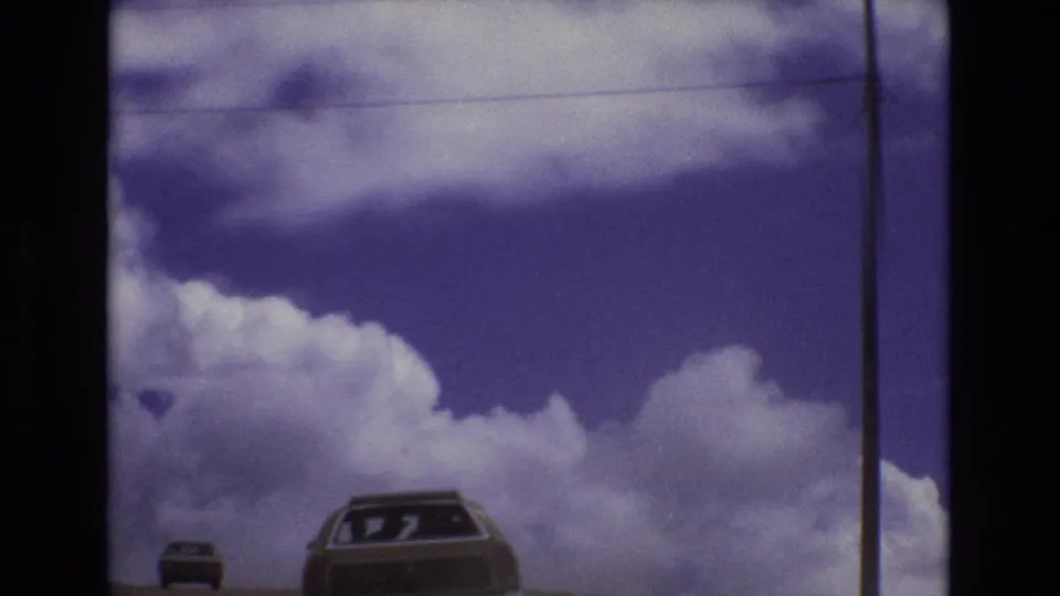 The final frame shows the station wagon and a smaller car near the bottom of the 1973 Colorado highway scene, with a tall utility pole, overhead wire, and soft cloud cover above.