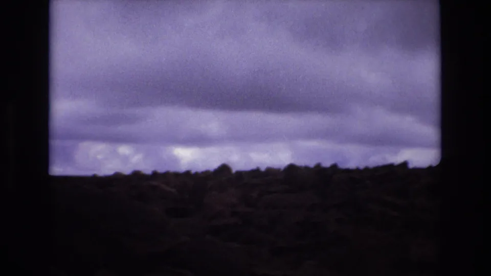 Colorado 1973 home-movie view of open terrain with a dark, layered cloud bank stretching across the frame.