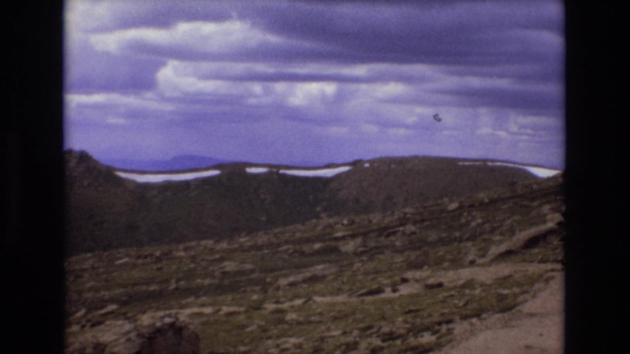Rocky mountain ridge with snow patches beneath layered clouds.