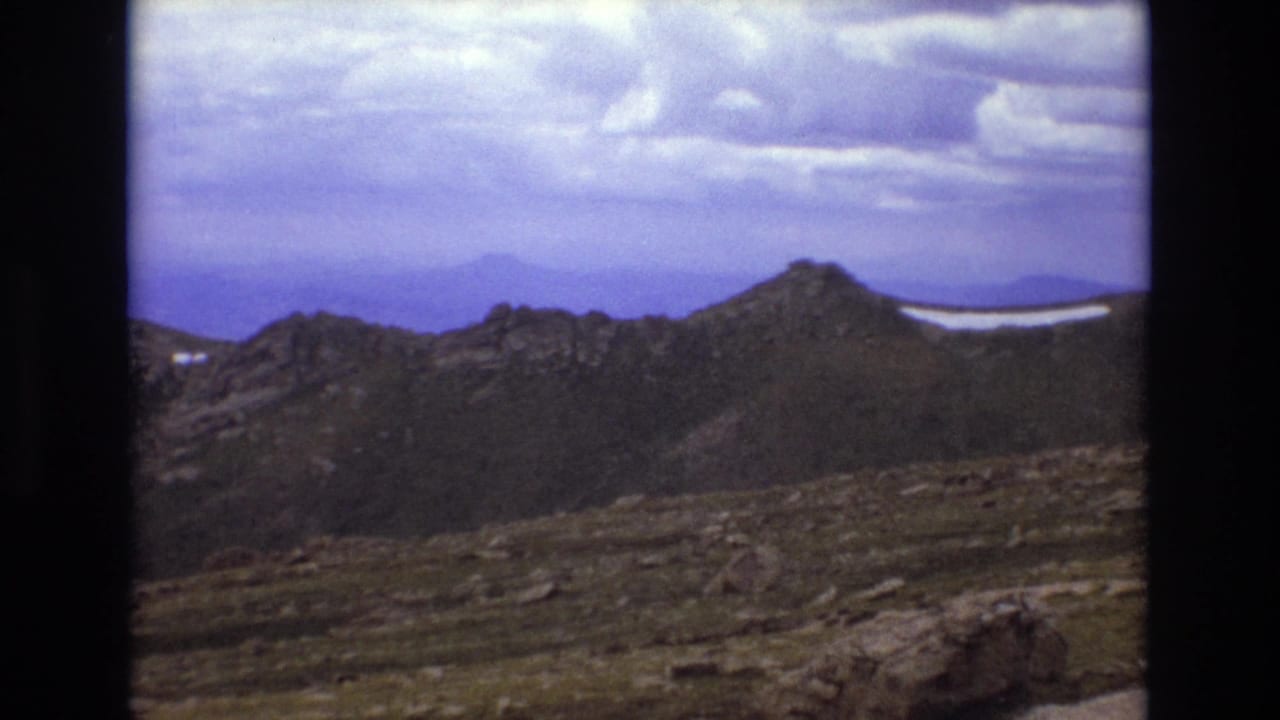 Mountain ridge and rocky slope under a broad cloudy sky.