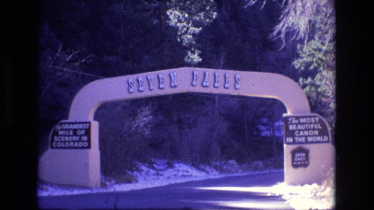 Seven Falls arch and entrance road framed by trees and snow.
