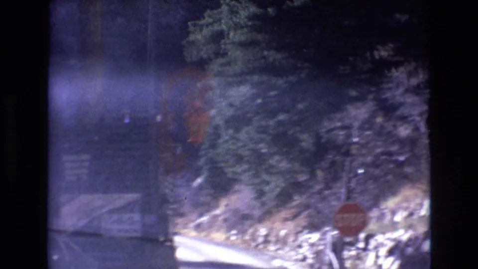 The final 1973 Colorado frame shows the moving car passing a red stop sign near a wooded roadside, with heavy motion blur and Super 8 color shift.