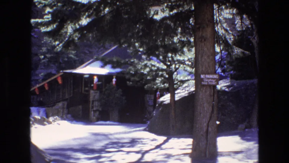 1973 Colorado 8mm still showing the same wooded attraction approach, with the no-parking sign on a tree and a rustic structure set back in shadow.