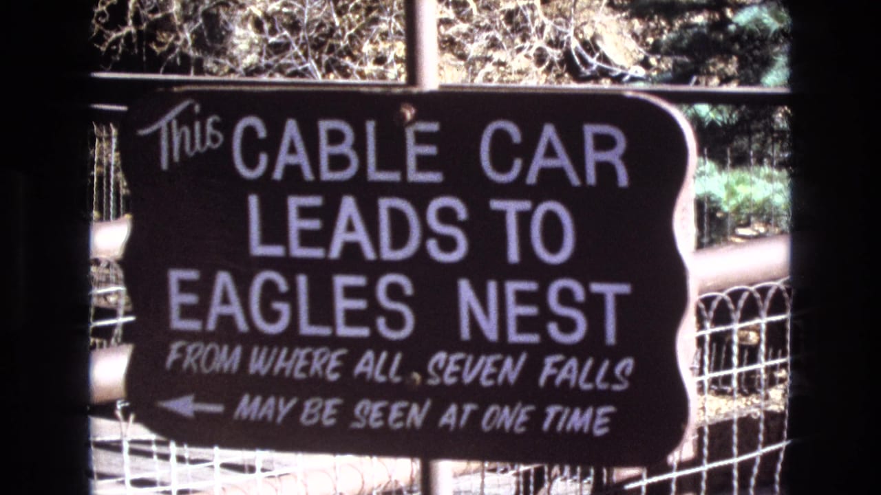 Close-up of a dark sign reading that the cable car leads to Eagles Nest and Seven Falls.