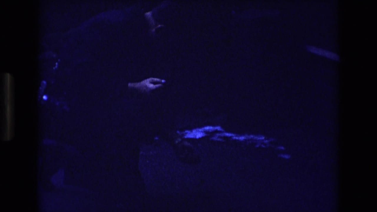 Partial person in darkness with a hand extended above a glowing blue shape near the lower frame.