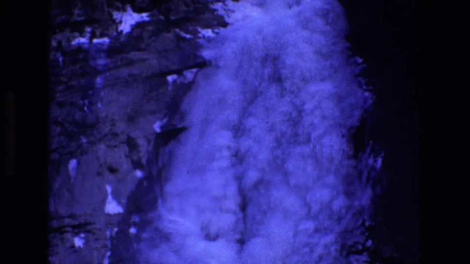 1973 Colorado home-movie frame showing a blue-tinted cloud or fog mass over dark rock textures, with visible film contact-sheet borders.