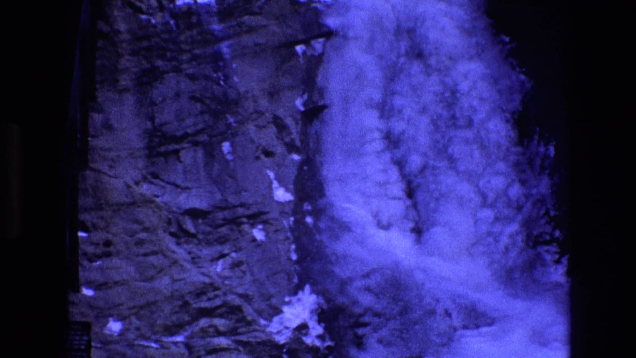 Blue-tinted waterfall spilling down a rocky cliff with snow or ice near the base.