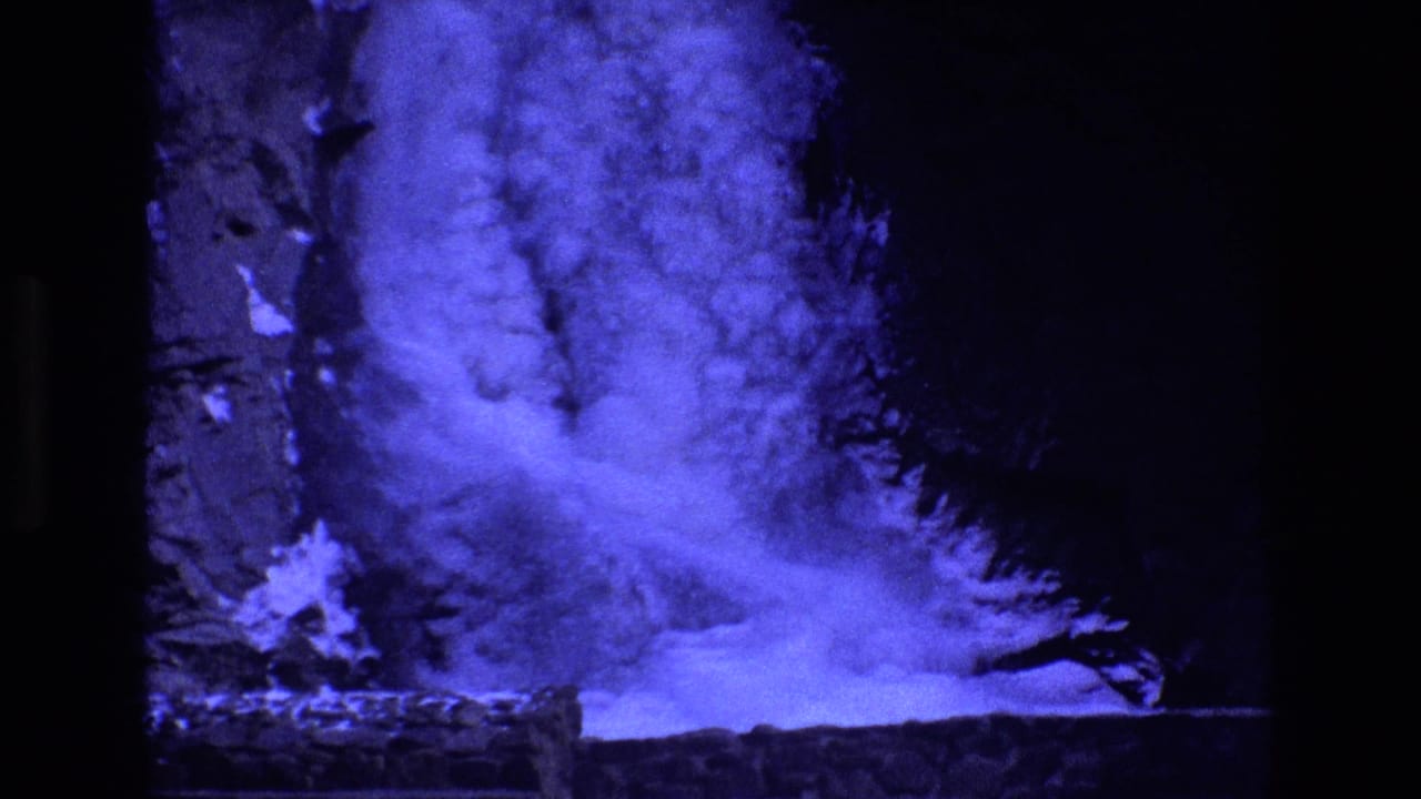 1973 Colorado 8mm frame showing a blue-tinted frozen waterfall base, dense ice texture, snow or frozen spray, and a dark rock face.