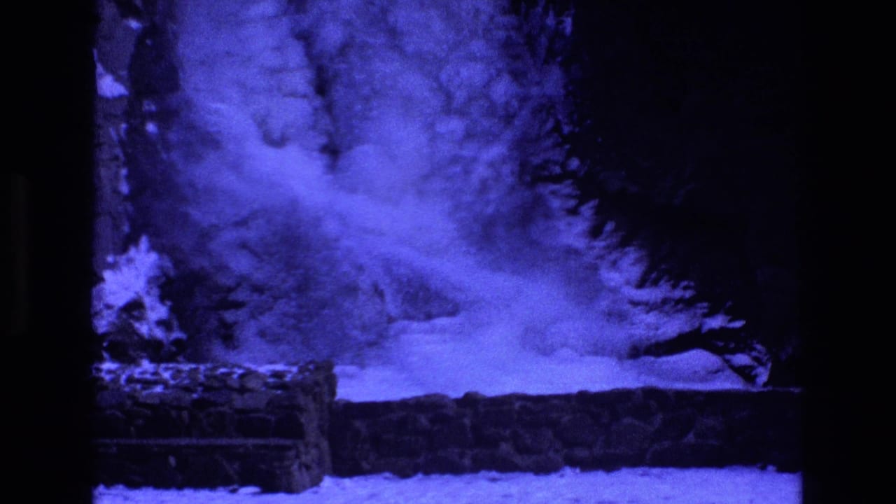 Icy water flows below a frozen cascade beside a stone ledge.