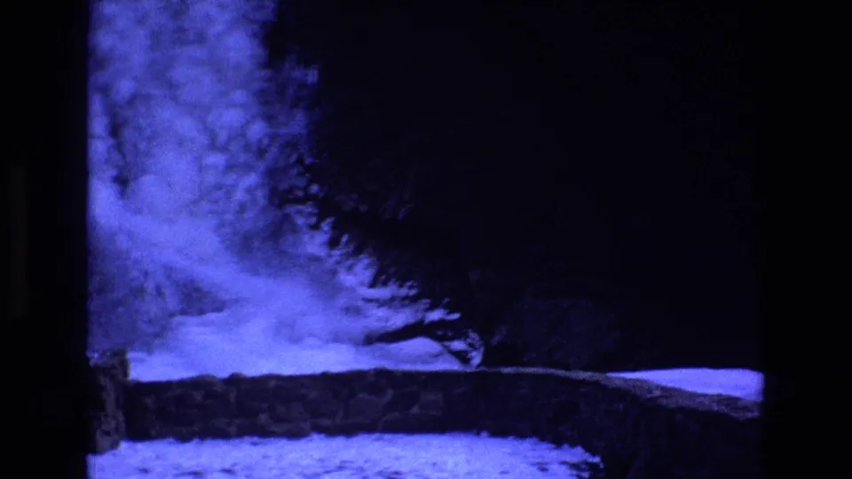 Blue-tinted final frame from the Colorado home movie showing a frozen stream or waterfall area, snow-covered ground, and dark trees around the water.