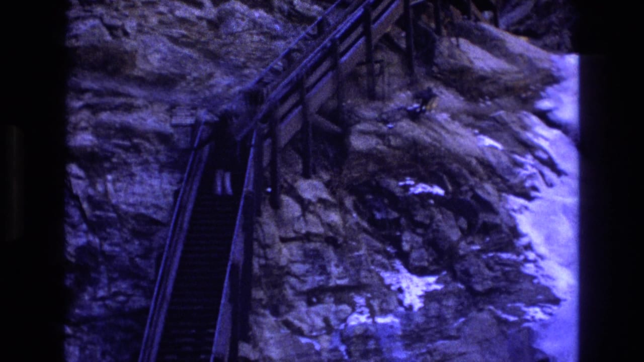 Rock face with steep stairs and railings beside a bright rocky chute.