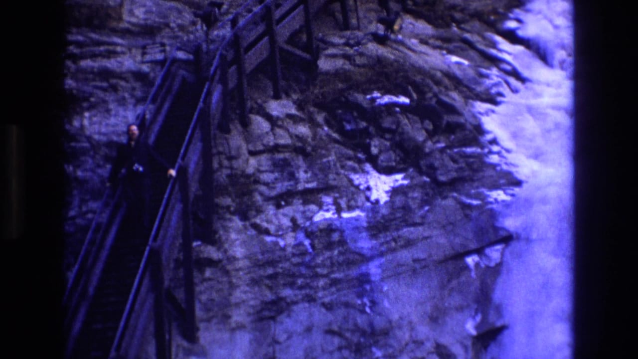 Visitor on narrow stairs beside rock wall and bright snowy edge.