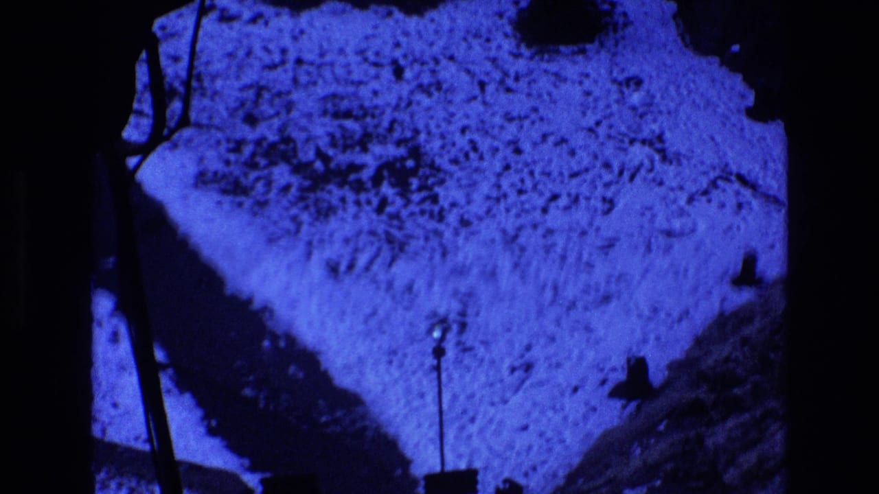 Snowy ground and dark walkway edges under a strong blue night tint.