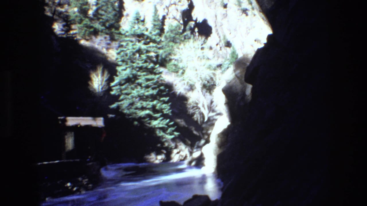 Narrow canyon walkway bordered by rock walls and evergreen trees.