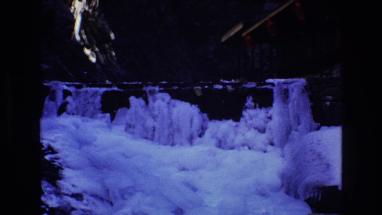 Blue-lit ice formations fill the lower frame beneath a dark rocky wall.