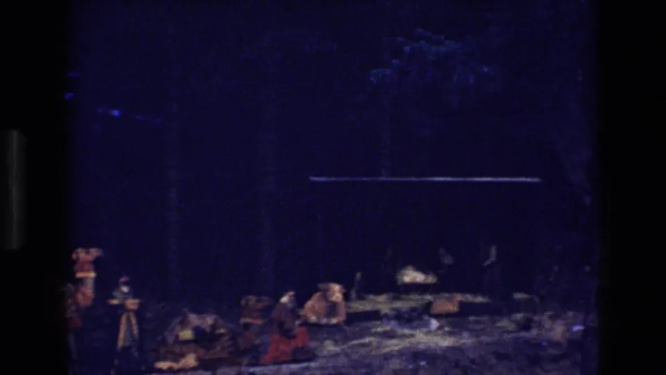 The final frame shows the camel train receding into a dark blue wooded setting, with people and saddled animals visible in low light.