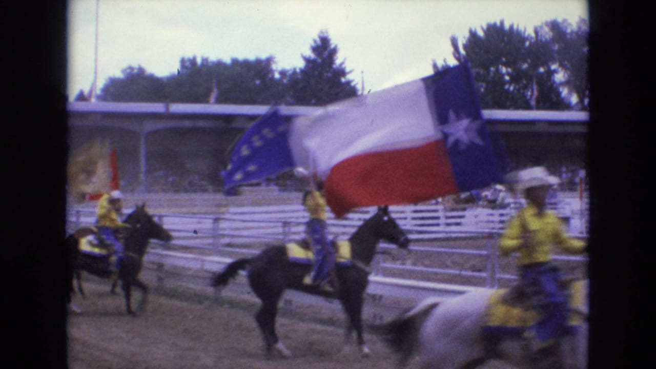1973 Colorado Springs rodeo footage shows riders in yellow shirts and white cowboy hats carrying flags on horseback in a dirt arena.