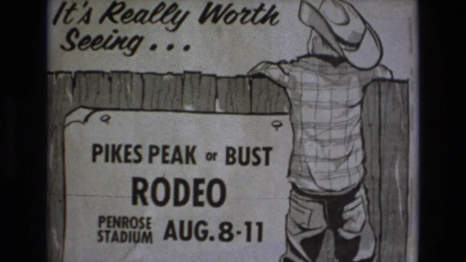 1973 Colorado Springs 8mm still showing the lower framing of a Pikes Peak or Bust Rodeo poster with event dates and a cowboy figure at right.
