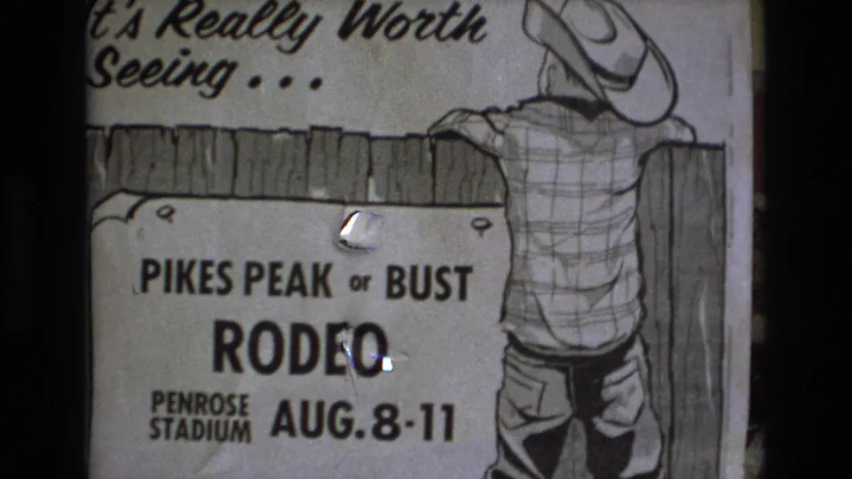 1973 Colorado Springs 8mm frame showing a hand-drawn Pikes Peak or Bust Rodeo poster for Penrose Stadium with a cowboy figure leaning over a wooden fence.