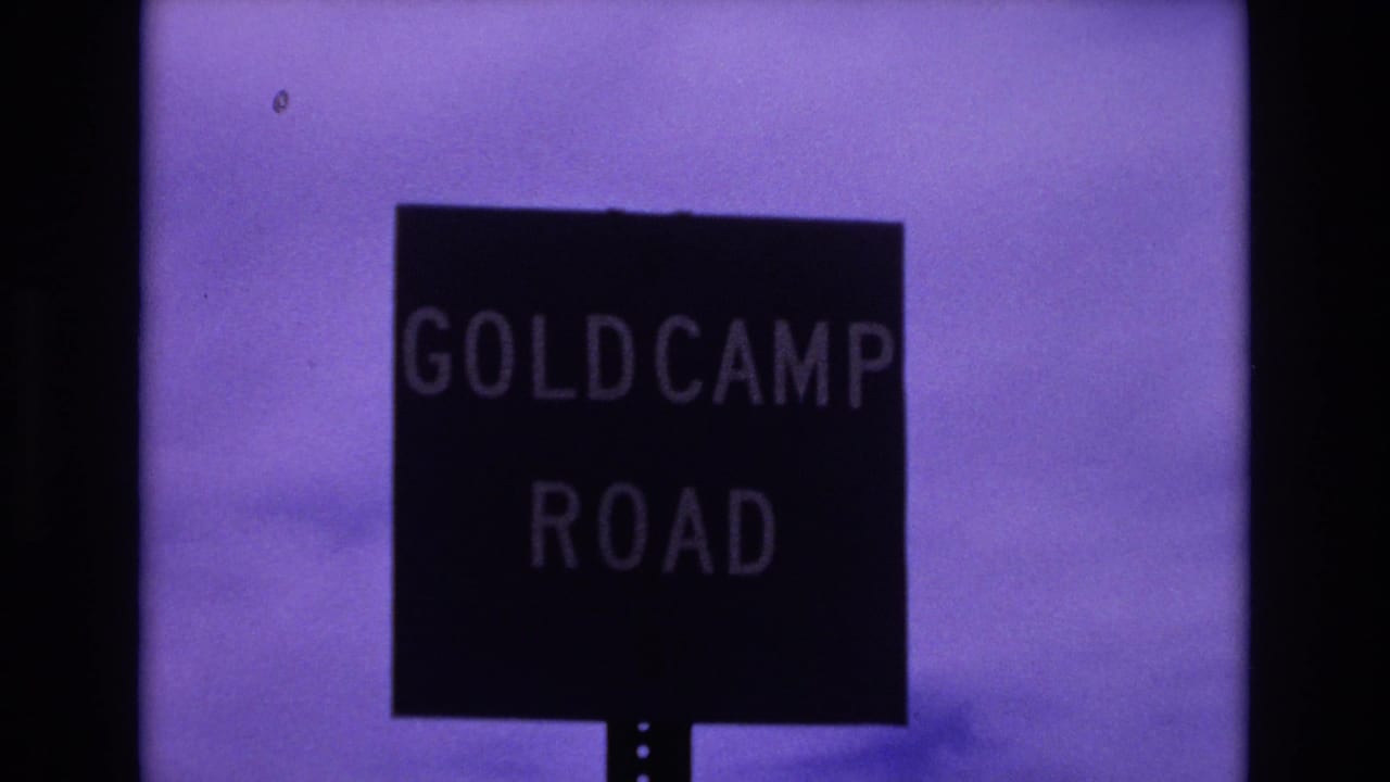 1973 Colorado Springs 8mm frame with the Goldcamp Road sign centered below a faded purple sky and soft horizon.