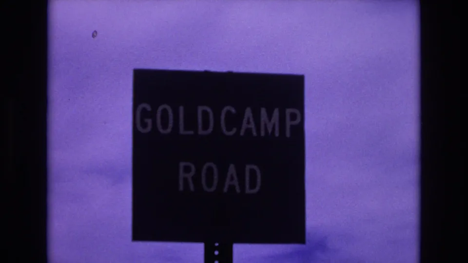 1973 Colorado Springs 8mm frame with the Goldcamp Road sign centered below a faded purple sky and soft horizon.