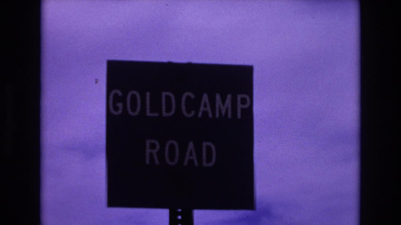Black Goldcamp Road sign against a purple-tinted sky.