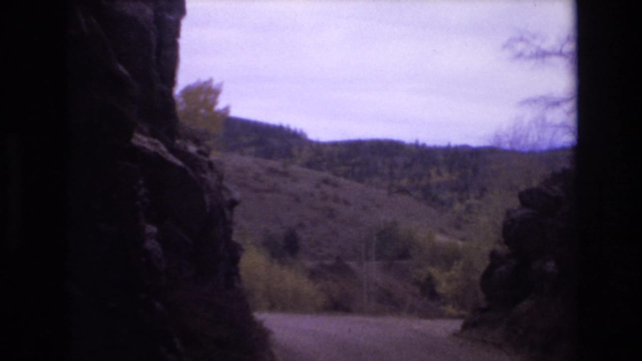 A roadside mountain view appears between dark rock edges.