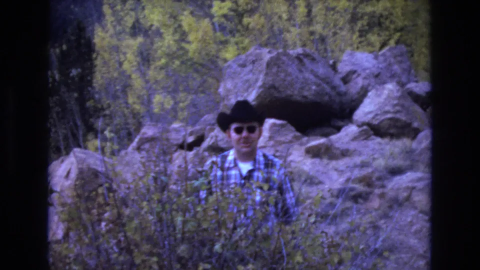 The final frame shows the adult man standing nearly front-facing in a cowboy hat and sunglasses, surrounded by dry brush, large rocks, and trees in Colorado Springs.