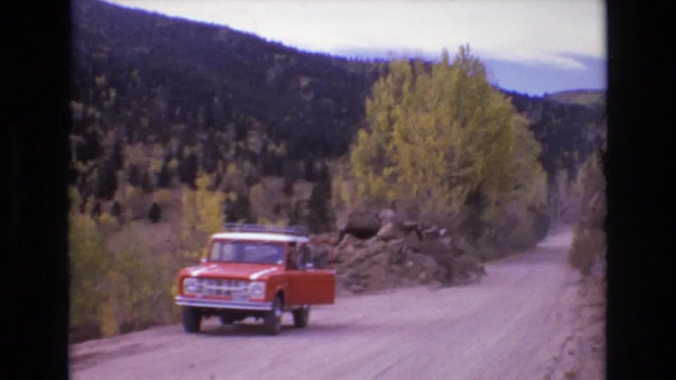 Final frame shows the red Ford Bronco on the mountain dirt road near a rock pile, with a person by the open door and wooded Colorado hills beyond.