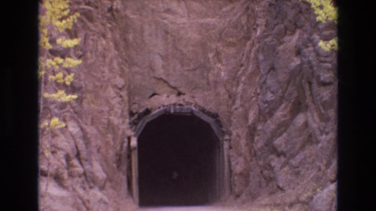 1973 Colorado Springs frame with the camera nearer to a shadowed tunnel entrance carved through a rocky cliff face.