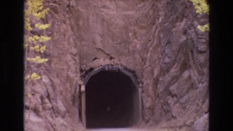 1973 Colorado Springs frame with the camera nearer to a shadowed tunnel entrance carved through a rocky cliff face.