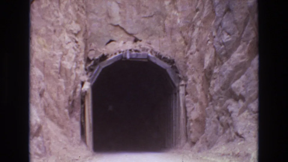 Final 1973 Colorado Springs frame showing the dark arched tunnel entrance close up, surrounded by pale and reddish rock textures.