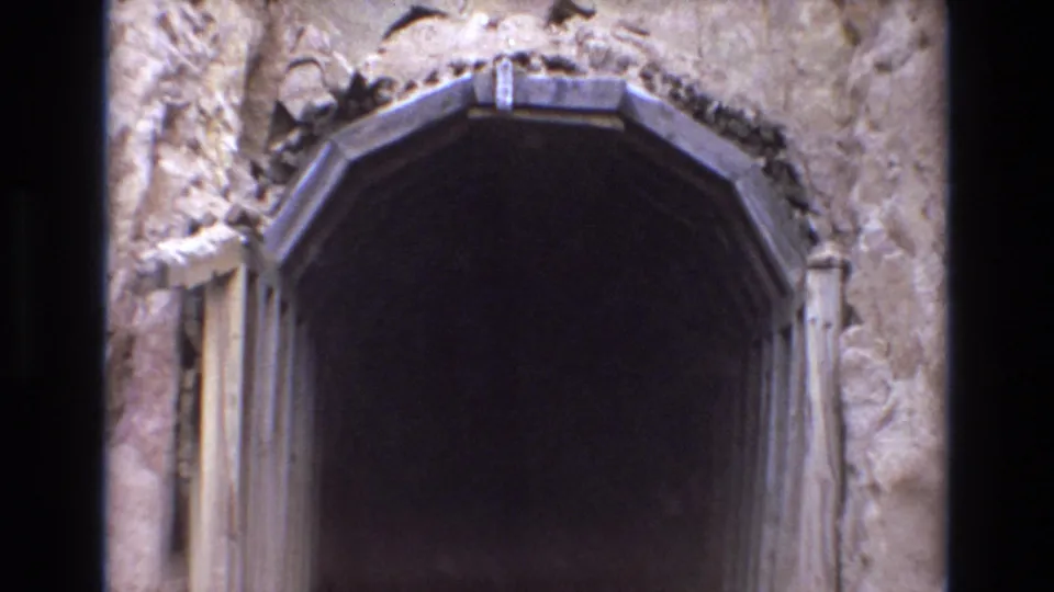 1973 Colorado Springs 8mm frame showing the zoom moving in on a mine-style arched entrance, with wood framing and textured rock filling the edges.