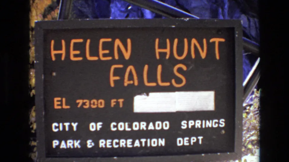 The Helen Hunt Falls sign fills the frame, identifying the Colorado Springs park location with elevation text and municipal park department wording.