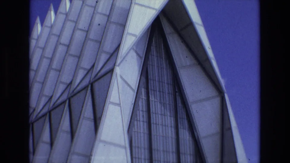 1973 Colorado Springs 8mm frame with a close low-angle view of the United States Air Force Academy Chapel's angular exterior, tall windows, and repeating triangular forms.