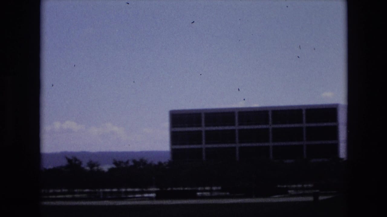 A modernist base building and low tree line sit against distant hills, continuing the metadata-supported 1973 Colorado Springs Air Force base exterior view.