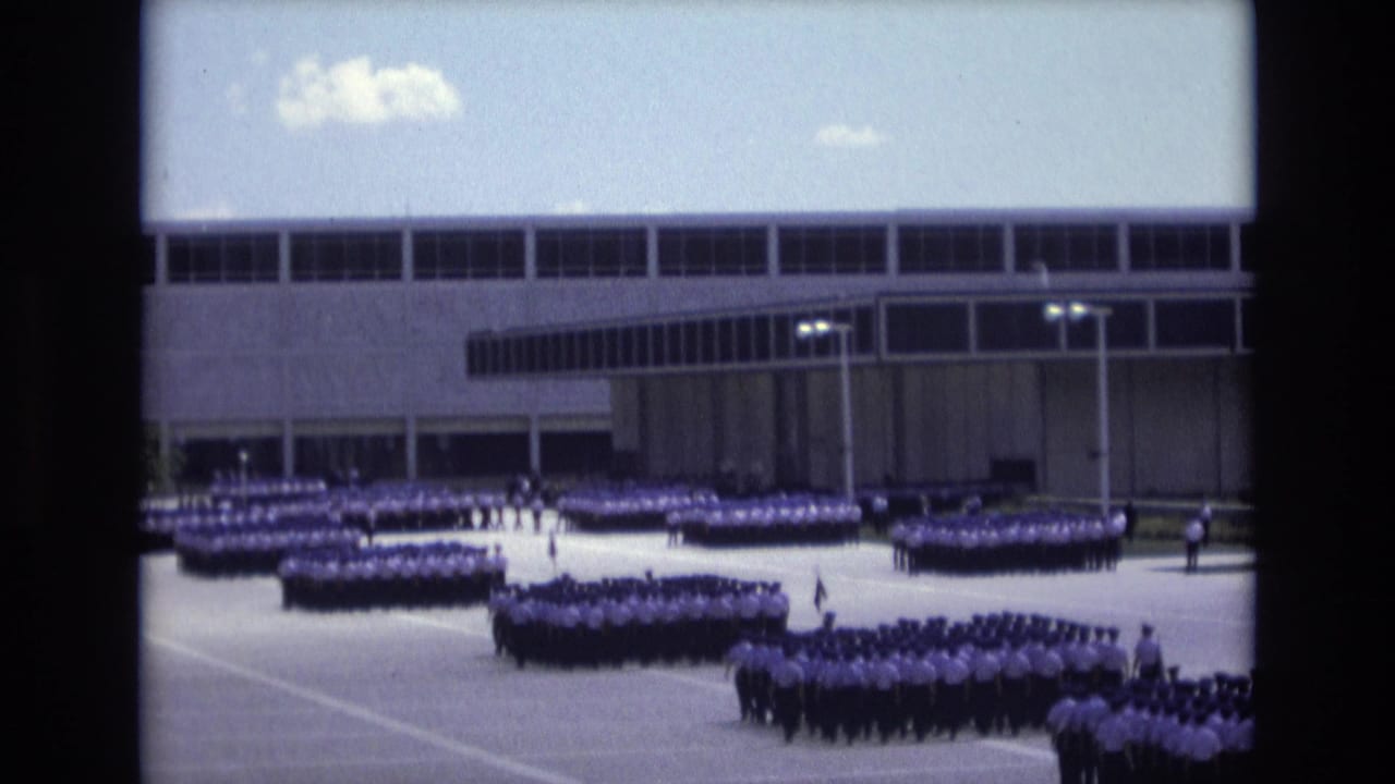 1973 Colorado Springs 8mm frame showing uniformed military or cadet ranks arranged across a paved courtyard in front of a modern institutional building.