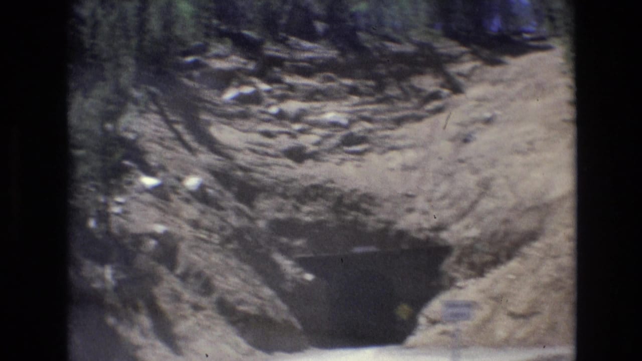 Closer view of a dark tunnel entrance surrounded by rocky slopes.
