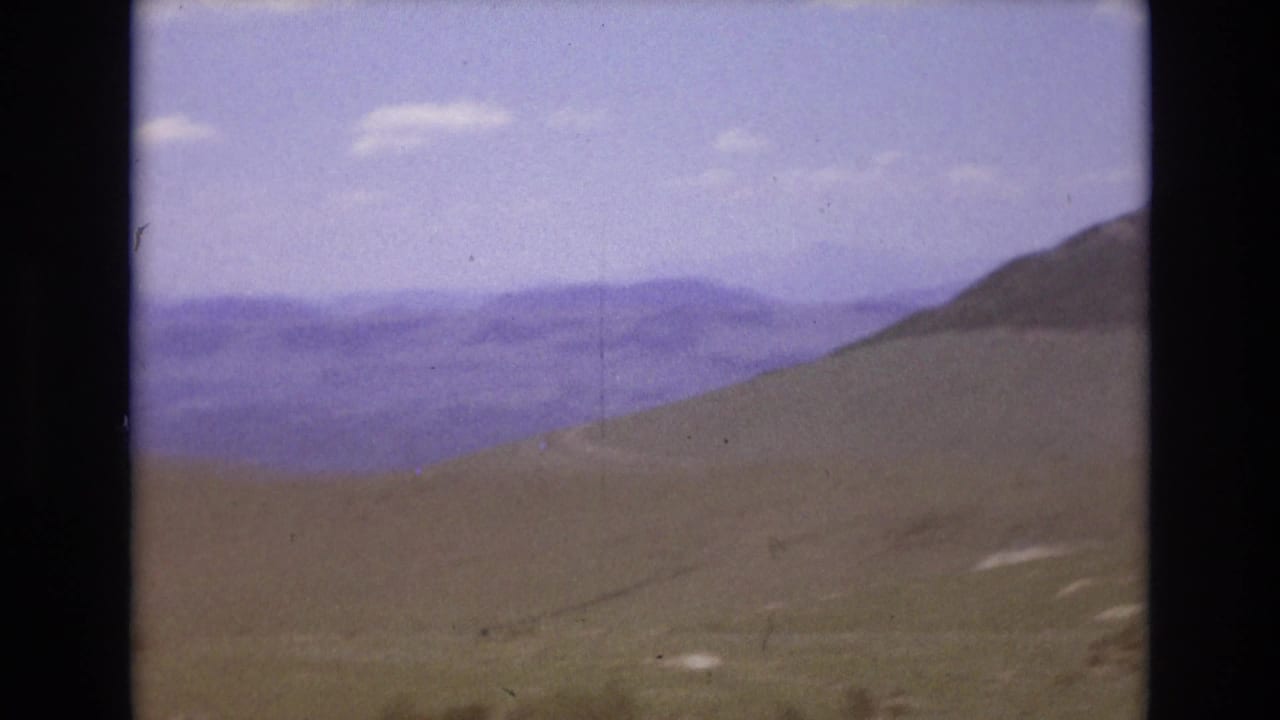 Open mountain slope with distant ranges under a hazy sky.