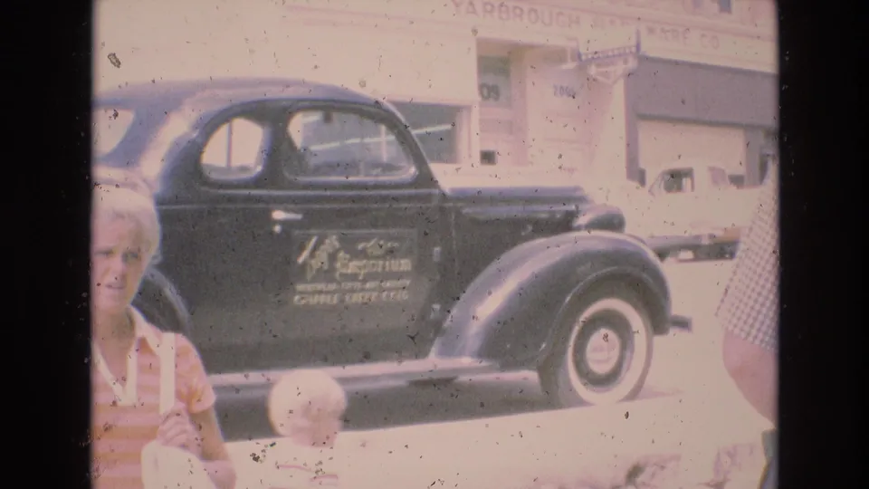 1973 Colorado Springs street scene with a woman and child in the foreground near a black coupe with whitewall tires parked outside the Yarbrough Hardware Co. building.