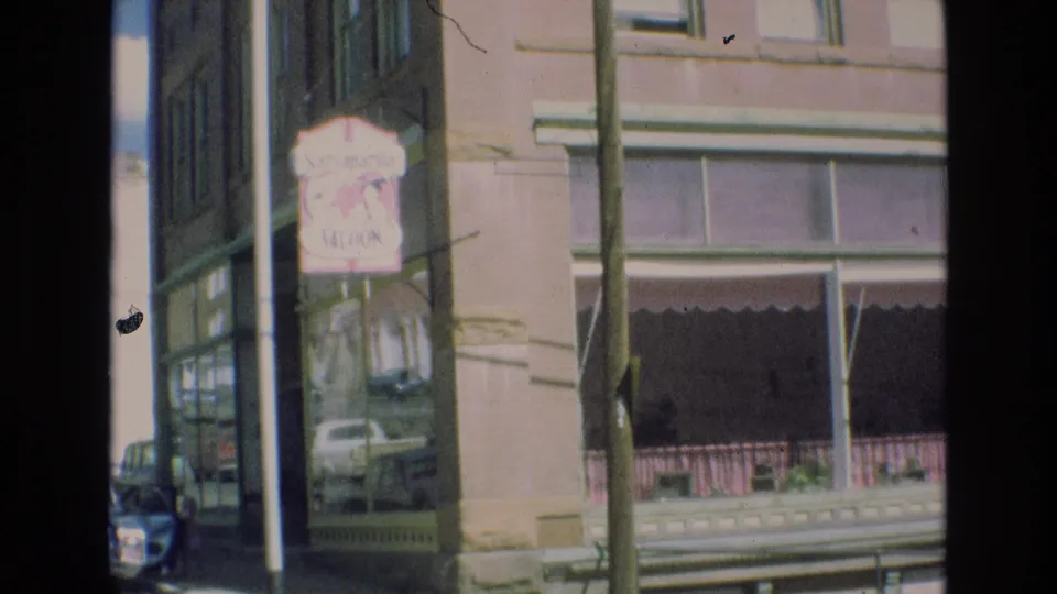 Colorado Springs storefront view from 1973 with the Saraparilla Saloon sign, upper windows, awning, and street fixtures visible in soft 8mm color.