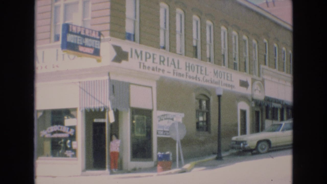 1973 Colorado Springs view of the Imperial Hotel-Motel corner facade with theatre, fine foods, and cocktail lounge wording, striped awnings, a pedestrian near the entrance, and a parked sedan along the curb.