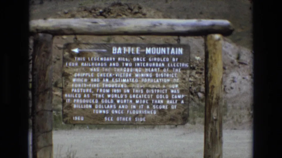 1973 home-movie view of the Battle Mountain historical marker, framed with its wooden support structure and the dry roadside landscape around it.