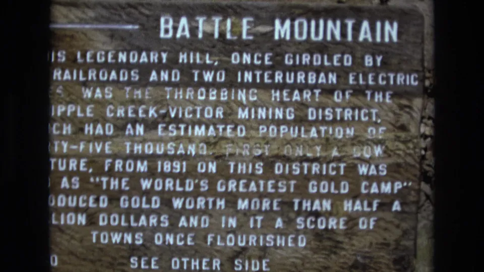 Final 8mm frame of the Battle Mountain historical marker, retaining the visitor-shot close-up and visible text about the gold camp and mining district.