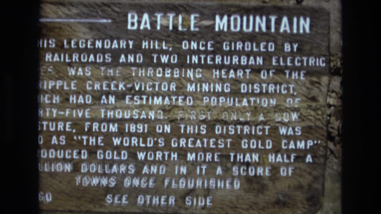 Another close view of the Battle Mountain sign with dense white text on a wooden surface.