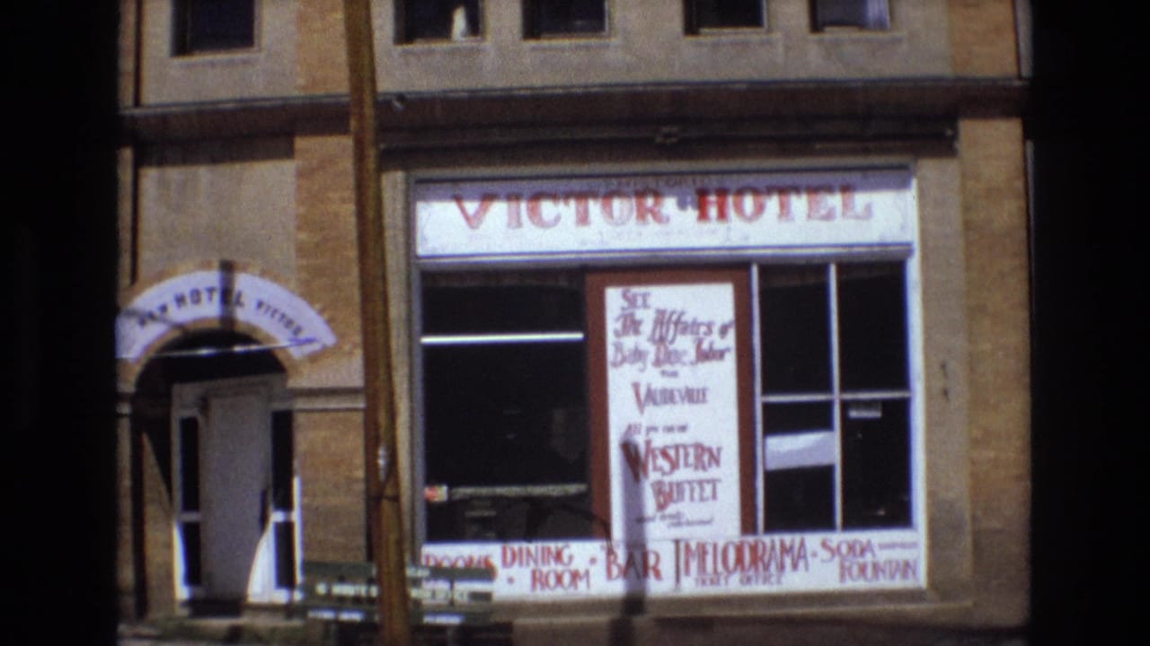 1973 Colorado Springs view of the Victor Hotel facade with brick exterior, arched entrance canopy, and signs for rooms, dining, bar, and entertainment.