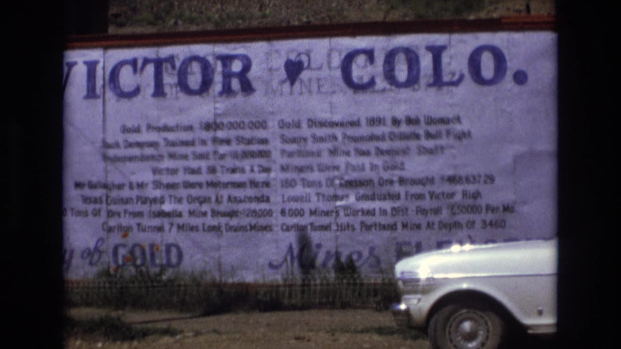 Victor, Colorado history sign with a white car visible near the lower right.