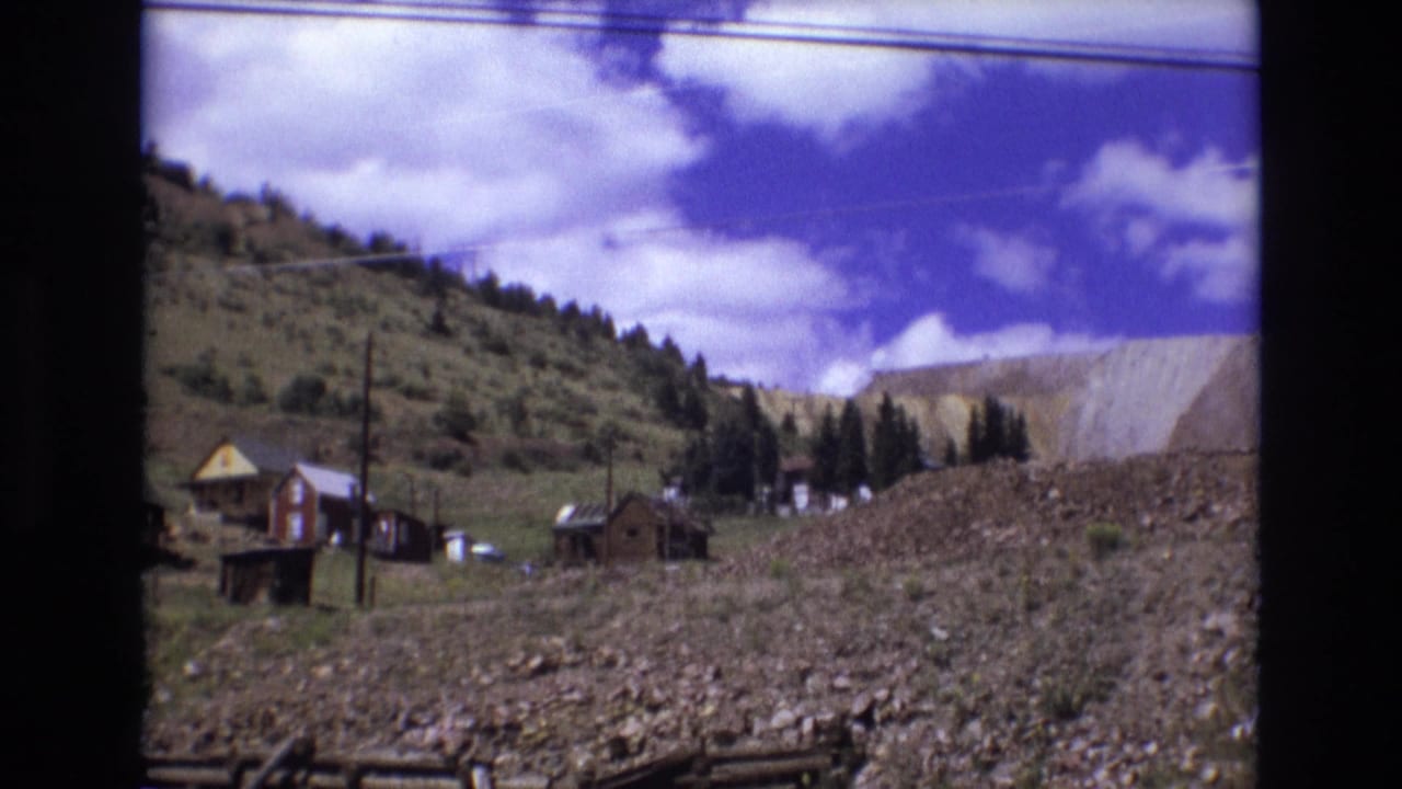 Hillside cabins and rocky ground with trees and utility poles in the distance.