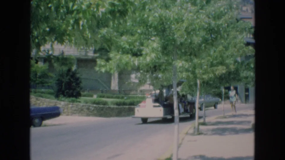The clip ends on a similar visitor-shot view of the Colorado Springs zoo grounds, with trees, a light-colored car, a darker car, distant people, and low stone landscaping.