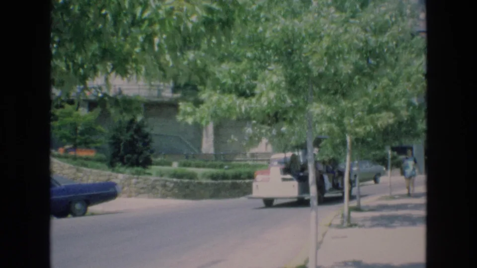 The 1973 Colorado Springs street view shows the tour vehicle moving away under trees, with a sidewalk pedestrian and buildings partly obscured by foliage.